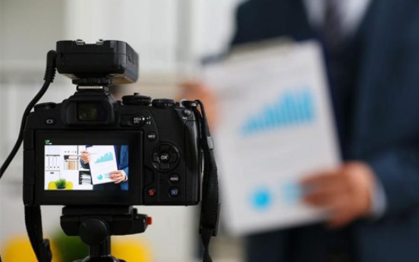 Primer plano de una cámara de video grabando a un miembro del equipo durante la creación de contenido, ilustrando el servicio de videomarketing corporativo.